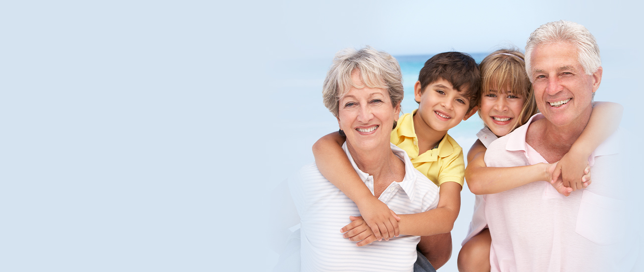 Grandparents with two grandchildren smiling against a blue background.